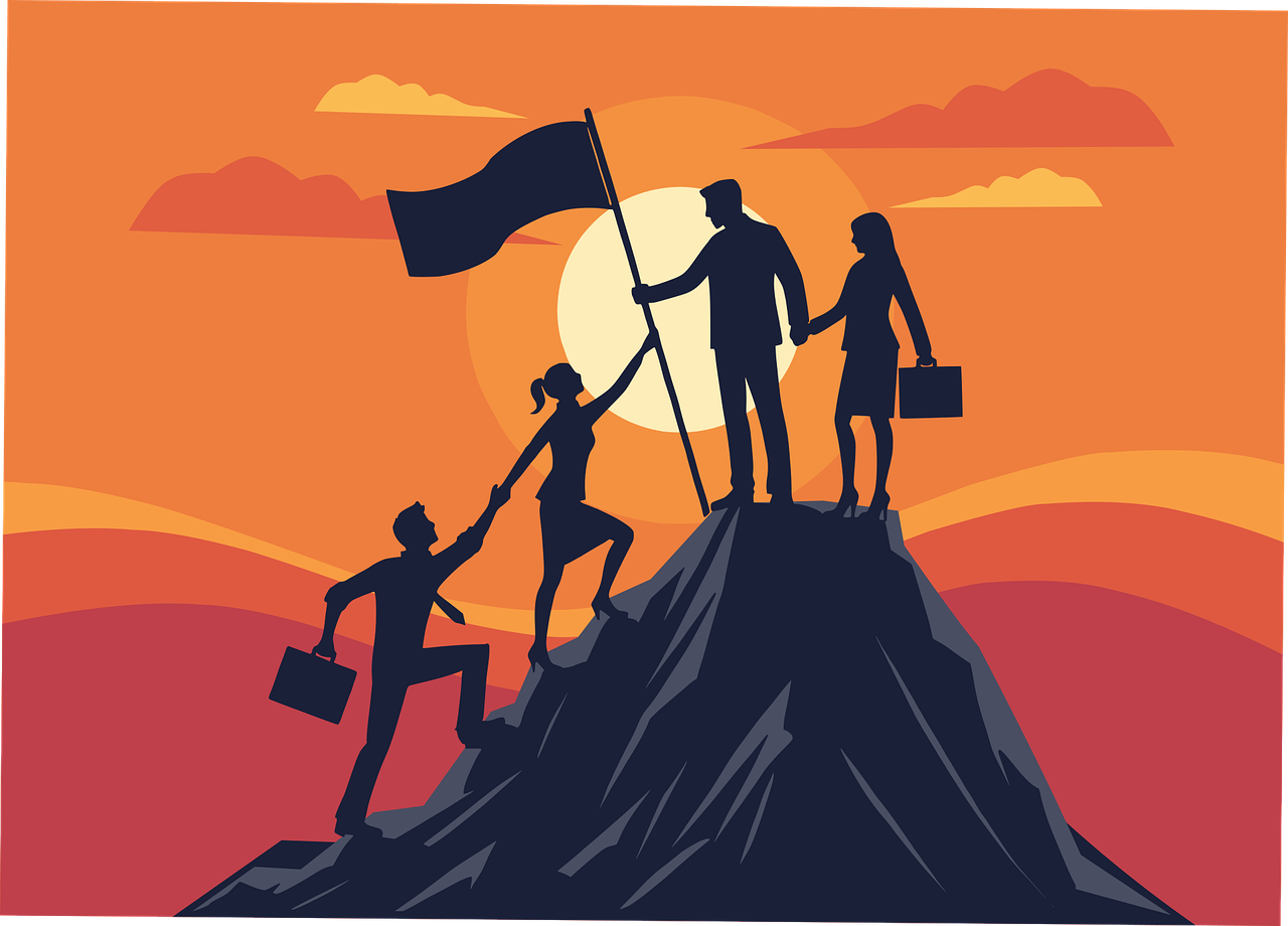夕焼けのなか山頂に立ち旗を立てる人々