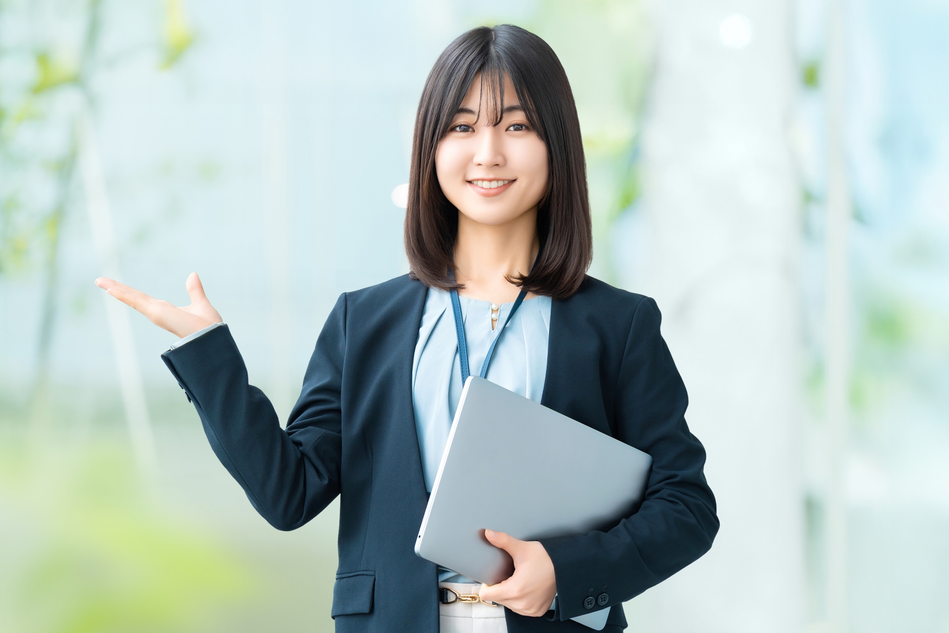 ノートPCを抱えて右手で案内する女性