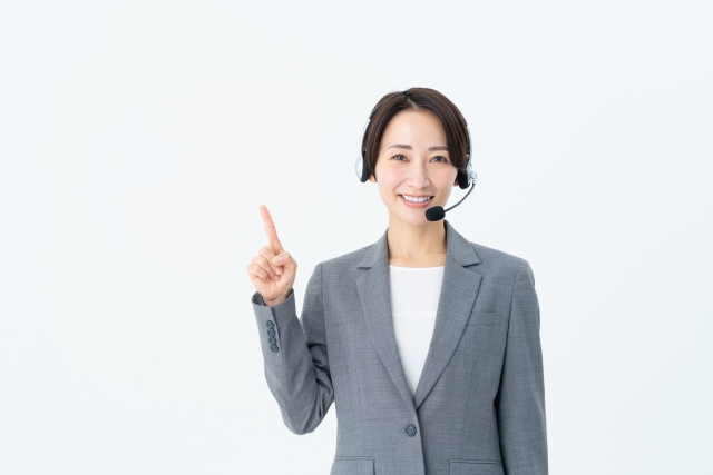 ヘッドセットをつけた指差しポーズの女性