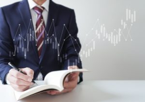 ペンを持って読書をするスーツ姿の男性とチャート