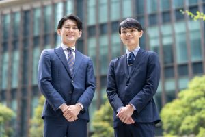 ビルを背景に立つ2人のビジネスパーソン