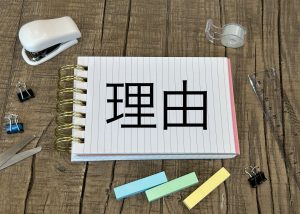 理由と書かれたメモ帳と文房具