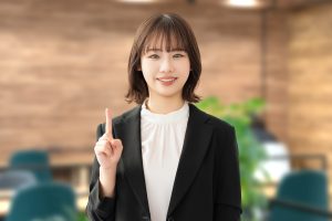 人差し指を立てる女性ビジネスパーソン