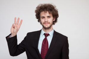 指を3本立てる外国人ビジネスパーソン